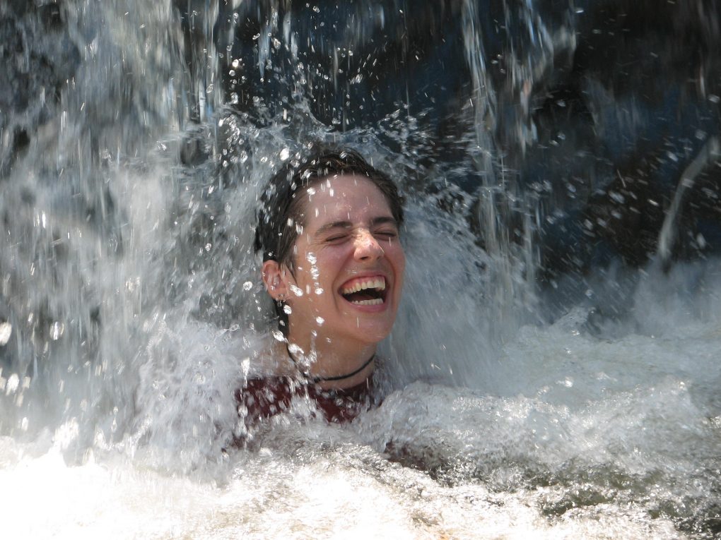 Woman smiling under waterfall